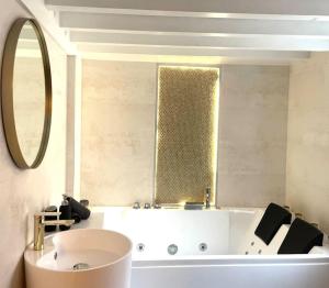 een badkamer met een bad, een wastafel en een spiegel bij Logement de charme avec balnéo in Lyon
