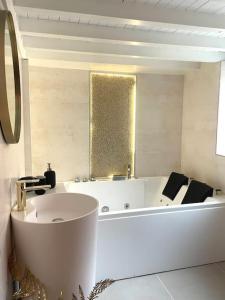 een witte badkamer met een bad en een wastafel bij Logement de charme avec balnéo in Lyon