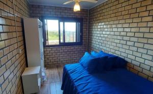 Un dormitorio con una cama azul y una pared de ladrillo en Residencial Itapeva, en Torres