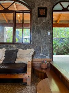 Habitación con sofá y pared de piedra. en Casa Qatzij - Guest House, Lake Atitlan en San Lucas Tolimán