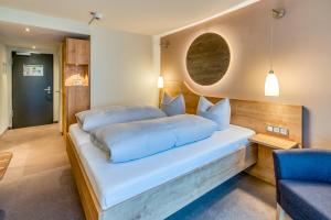 a bedroom with a white bed and a blue chair at Hotel Beckmann in Göttingen