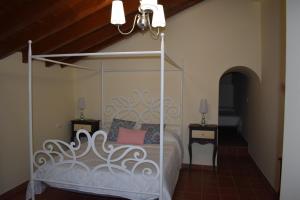 1 dormitorio con 1 cama blanca con dosel y 2 mesitas de noche en Hotel Rural El Refugio de Los Templarios en Cabeza del Buey