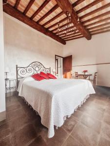 a bedroom with a large white bed with red pillows at Antica Torre del Borgo in Certaldo