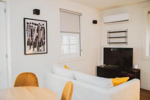 a living room with a white couch and a tv at Casa de Couros in Guimarães