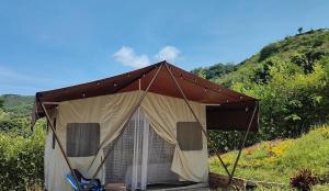 a brown tent with chairs in a field at Glamping Paraíso Escondido in Anapoima