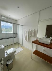 La salle de bains est pourvue de toilettes, d'un lavabo et d'un miroir. dans l'établissement Villa Dei Fiori, à São Sebastião