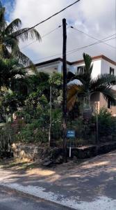 un panneau de rue devant une maison plantée de palmiers dans l'établissement Résidence au bout du Morne, au Morne
