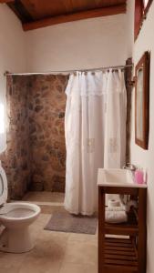 a bathroom with a white shower curtain and a toilet at 7 Colores Casas Serranas in San Marcos Sierras