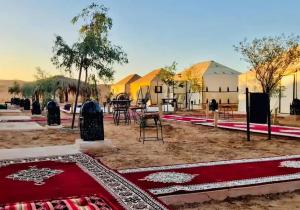a group of tents in a desert with a red rug at Merzouga best camp in Merzouga