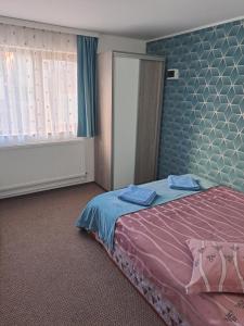 - une chambre dotée d'un lit avec un couvre-lit rose et bleu dans l'établissement Vila Lavinia, à Buşteni