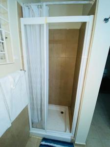 y baño con ducha y puerta de cristal. en Club Caribbean Apartments, en Runaway Bay