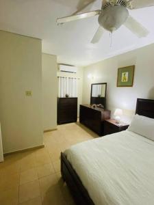 Club Caribbean Apartments في راناوي باي: غرفة نوم بسرير ومروحة سقف