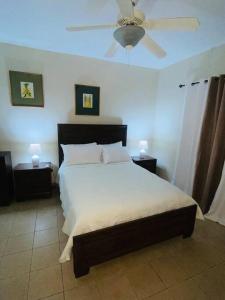 Club Caribbean Apartments في راناوي باي: غرفة نوم بسرير ومروحة سقف