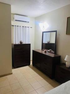 a bedroom with a dresser with a mirror and a dresser sidx sidx sidx at Club Caribbean Apartments in Runaway Bay