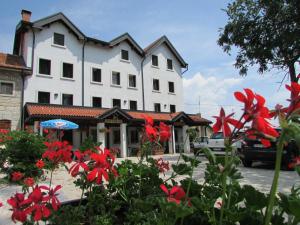 a white building with red flowers in front of it at Hotel Al Prato in Tonezza del Cimone