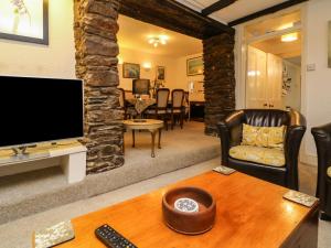 sala de estar con TV, sofá y mesa en Tythe Barn House, en Ilfracombe