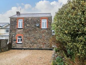 a stone house with red windows and a hedge at Tythe Barn House in Ilfracombe