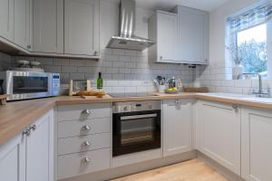 a white kitchen with white cabinets and a microwave at Wren Cottage in Stratford-upon-Avon