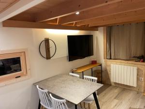 uma sala de jantar com uma mesa com cadeiras e uma televisão em Résidence Grand Roc - Bruyères 20 em Chamonix-Mont-Blanc