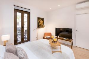 a white bedroom with a bed and a tv at BHost - Ferraz 74 in Madrid