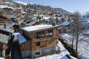 a wooden house in a snow covered village at Chalet Amis - Meribel - Pool moovie and play room in Méribel