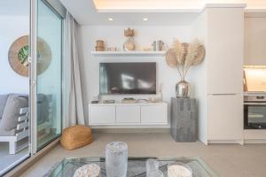 uma sala de estar com uma televisão e uma mesa de vidro em Puente Romano Hotel Apartment Marbella em Marbella