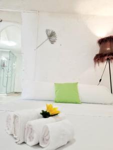 a white bedroom with a white bed with a yellow flower on it at Apartamentos La Cueva in Paterna