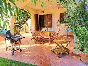 eine Terrasse mit einem Tisch, Stühlen und einem Grill in der Unterkunft Casa Eucalipto - Marina di campo, Elba in Marina di Campo