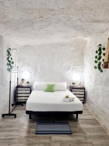 a bedroom with a white bed with a green pillow at Apartamentos La Cueva in Paterna