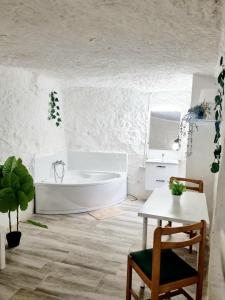 a white bathroom with a tub and a table at Apartamentos La Cueva in Paterna