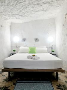a bedroom with a large white bed with two tables at Apartamentos La Cueva in Paterna