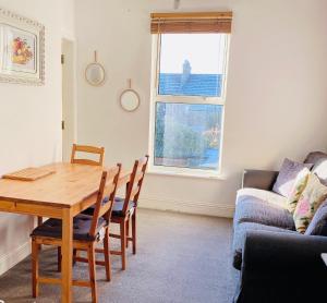 Charminster Homestay في بورنموث: غرفة معيشة مع طاولة خشبية وأريكة