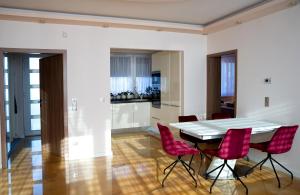 a dining room with a white table and red chairs at Dream Apartman 1 with Free Parking in Győr