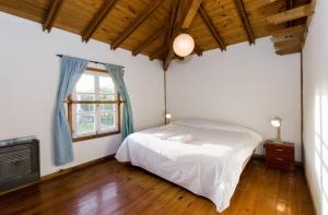 1 dormitorio con cama blanca y ventana en Gray Fox Apartments Casa La Rafaela en Ushuaia