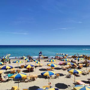 un groupe de personnes sur une plage avec des parasols dans l'établissement Parco del Mare - Relax near the sea and city centre, à Borghetto Santo Spirito