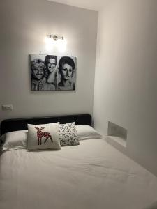 una camera con un letto bianco con due immagini sul muro di The Nest Of Via Toledo a Napoli