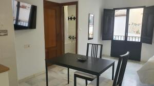 uma sala de jantar com uma mesa preta e cadeiras em CASA MORENA MiA APARTAMENTOS em Granada
