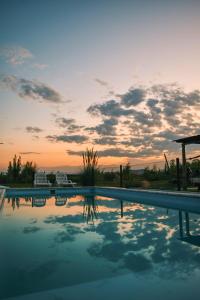 a swimming pool with a sunset in the background at casArtero eco posada in San Rafael