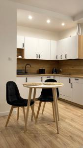 stół i krzesła w kuchni z białymi szafkami w obiekcie Nowoczesny Apartament w Dzierżoniowie - parter - balkon - pokój + sypialnia w mieście Dzierżoniów