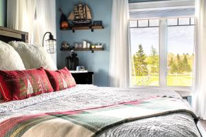 Un dormitorio con una cama con almohadas rojas y una ventana en Back Home Bed and Breakfast, en Membertou