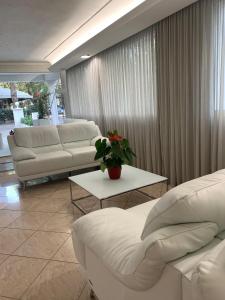 una sala de estar con 2 sofás blancos y una mesa. en Hotel Royal Plaza, en Rímini