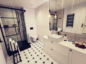 a white bathroom with a sink and a shower at Apartament 34 in Ciechanów