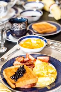 um prato de pequeno-almoço com ovos, torradas e frutas em Back Home Bed and Breakfast em Membertou