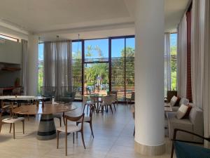 uma sala de jantar com mesas, cadeiras e janelas em Ilê de Pipa Blz em Pipa
