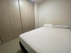 een wit bed in een kamer met een kast bij Apto a pasos del lago in Guatapé