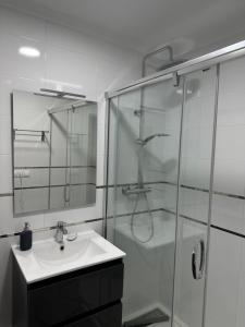 uma casa de banho com um lavatório e uma cabina de duche em vidro. em Bungalow Santa Pola del Este em Gran Alacant
