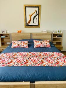 a bedroom with a bed with a blue comforter and pillows at Chez la Rose luxueuse cottage avec jacuzzi in Rouvres-la-Chétive