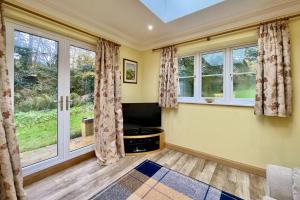 a living room with windows and a tv at Little Vintners in Thakeham