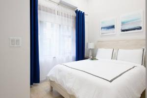 1 dormitorio con 1 cama blanca grande y cortinas azules en 78-4D Quality 1br W&D SKYLIGHT By Central Park en Nueva York