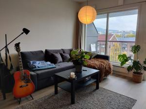 a living room with a couch and a guitar at Spacious and cozy study apartment with balcony in Oslo